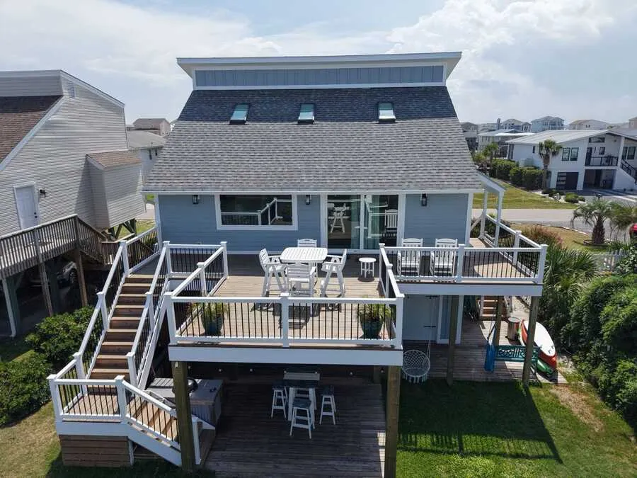 Aerial view of a raised beach home with a new composite deck and white rail stairs