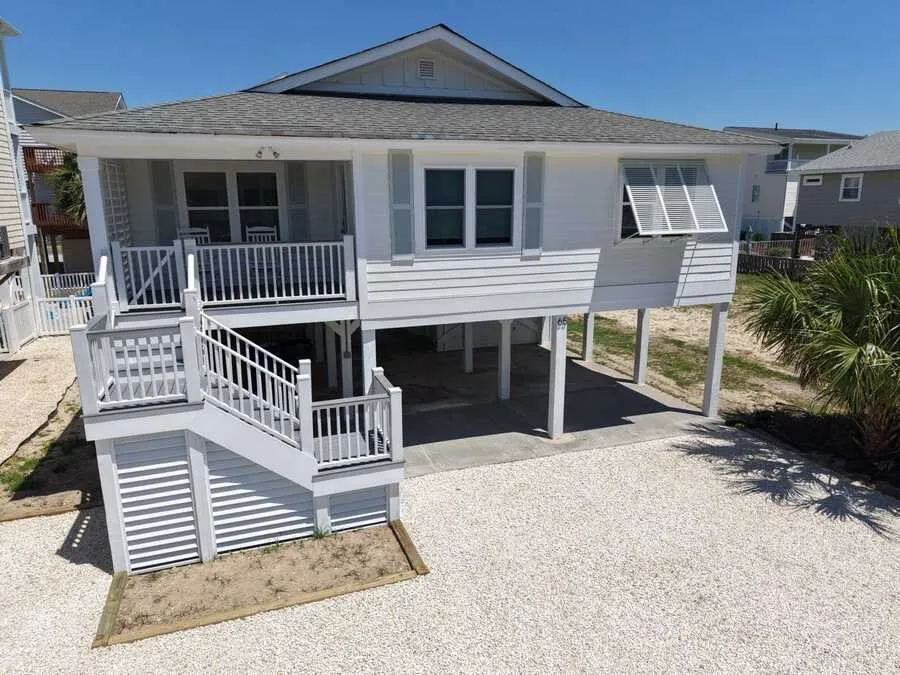 White raised beach house with new stairs and trim